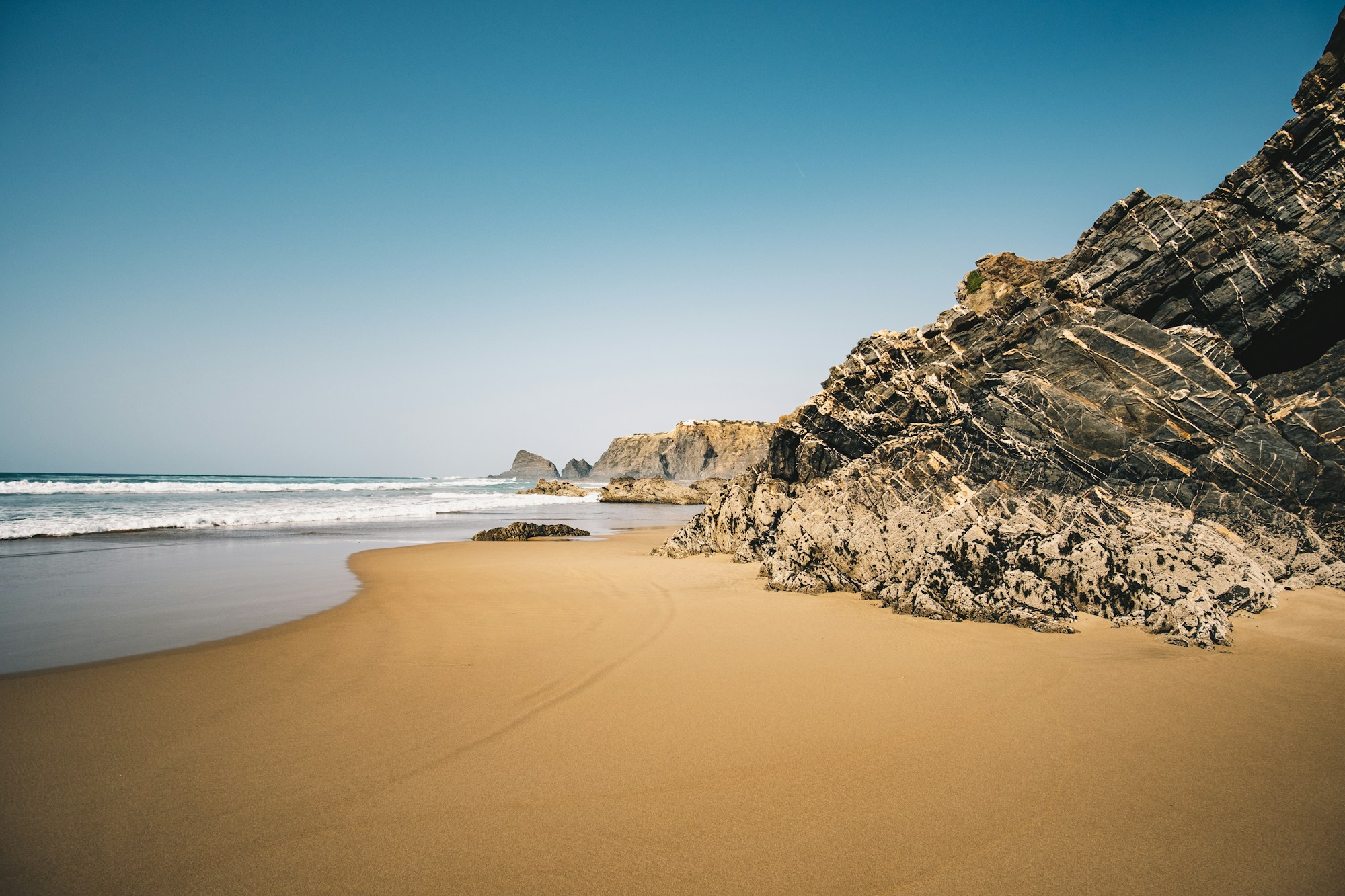 Golden sandy beach framed by ochre cliffs in the Algarve, Portugal