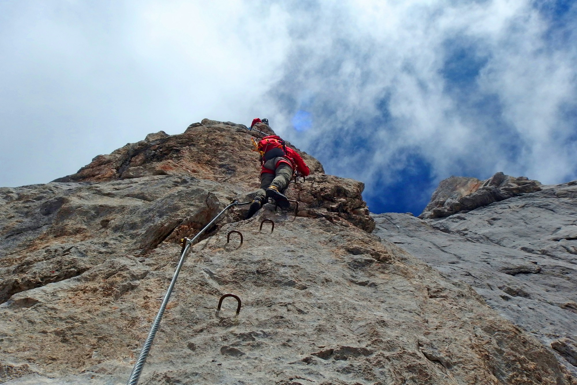 Via ferrata dans les Dolomites avec câbles et parois rocheuses calcaires, randonneurs avec équipement de sécurité
