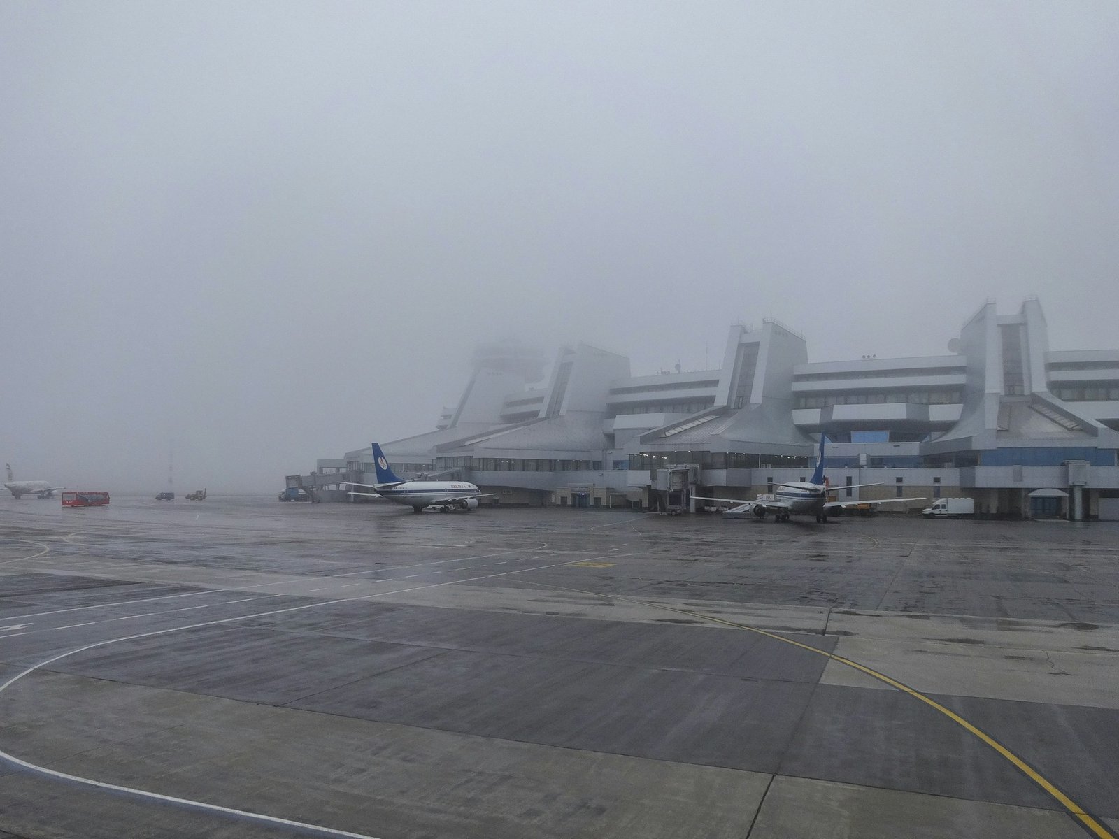 Terminal aeroportuale avvolto dalla nebbia con aerei fermi sul piazzale — crisi aerea Medio Oriente 2026