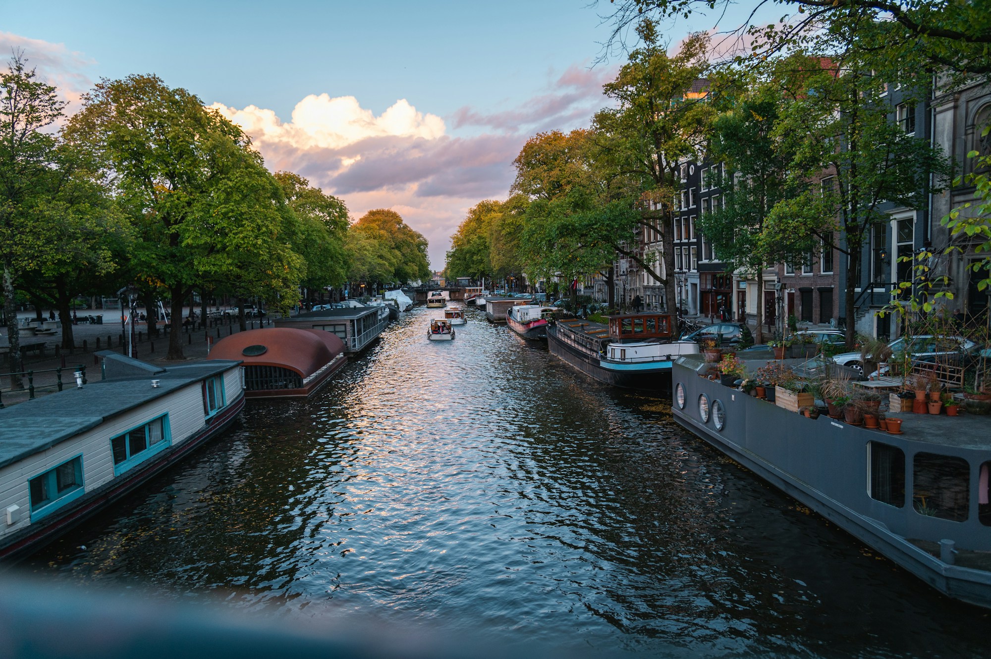 Houseboat moored on an Amsterdam canal, Netherlands, with typical facades in the background