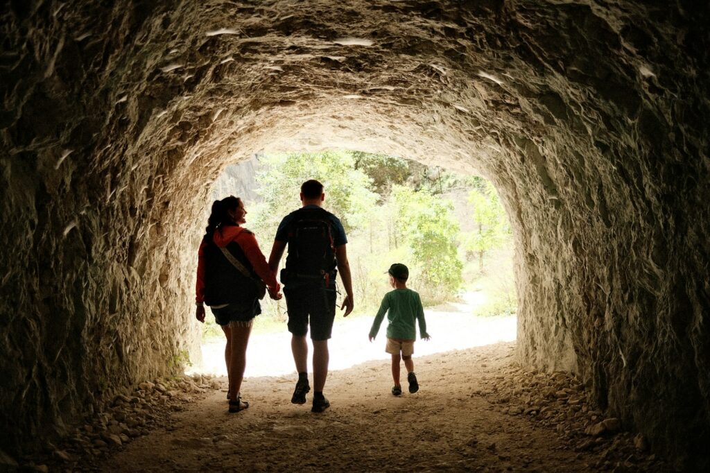 Famille marchant dans un tunnel de pierre baigné de lumière