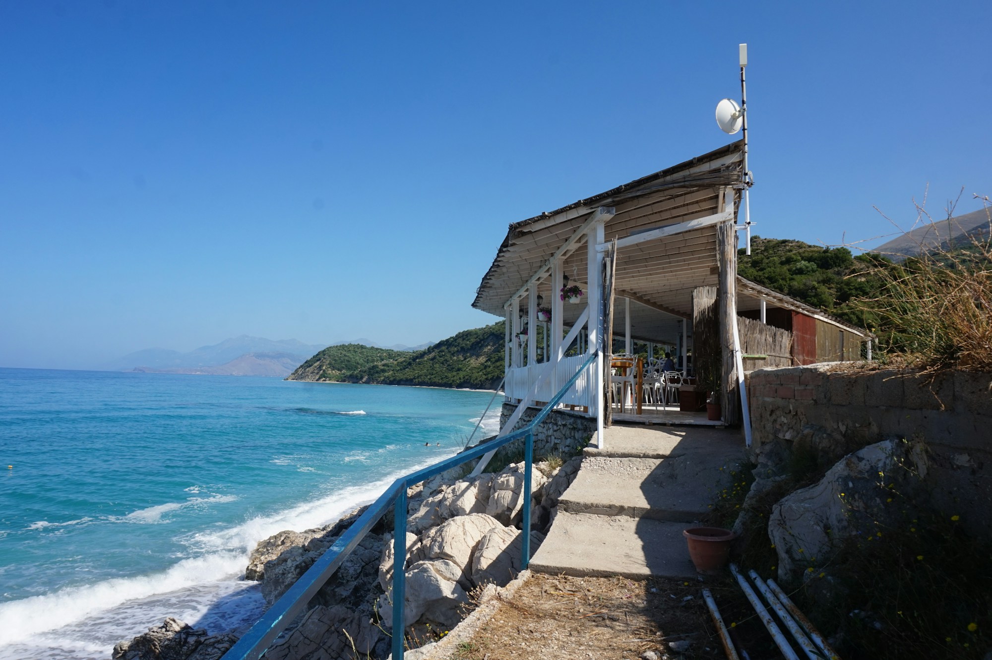 Bar de plage sur la Riviera albanaise avec eaux turquoise et montagnes en arrière-plan