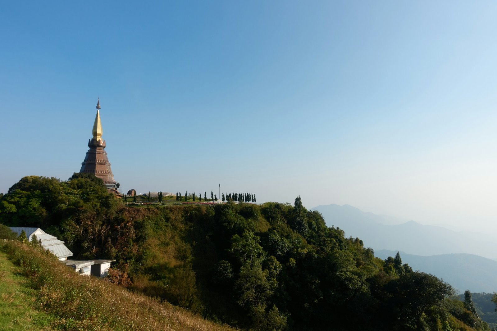 Golden temple in Chiang Mai surrounded by lush green mountains in Thailand