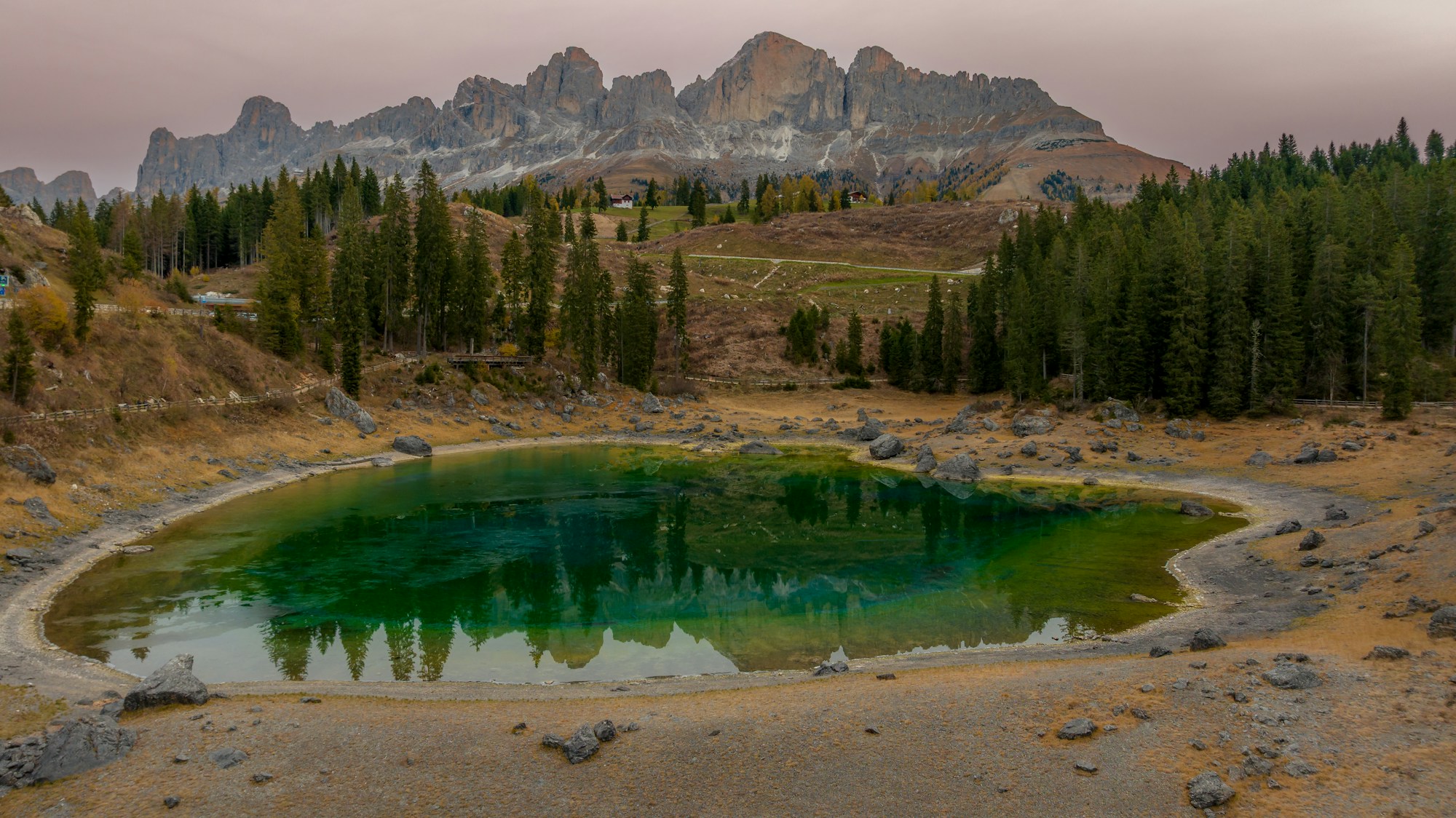 Lac émeraude reflétant les pics dentelés des Dolomites et les forêts de pins — cadre de l'étape reine du Giro 2026