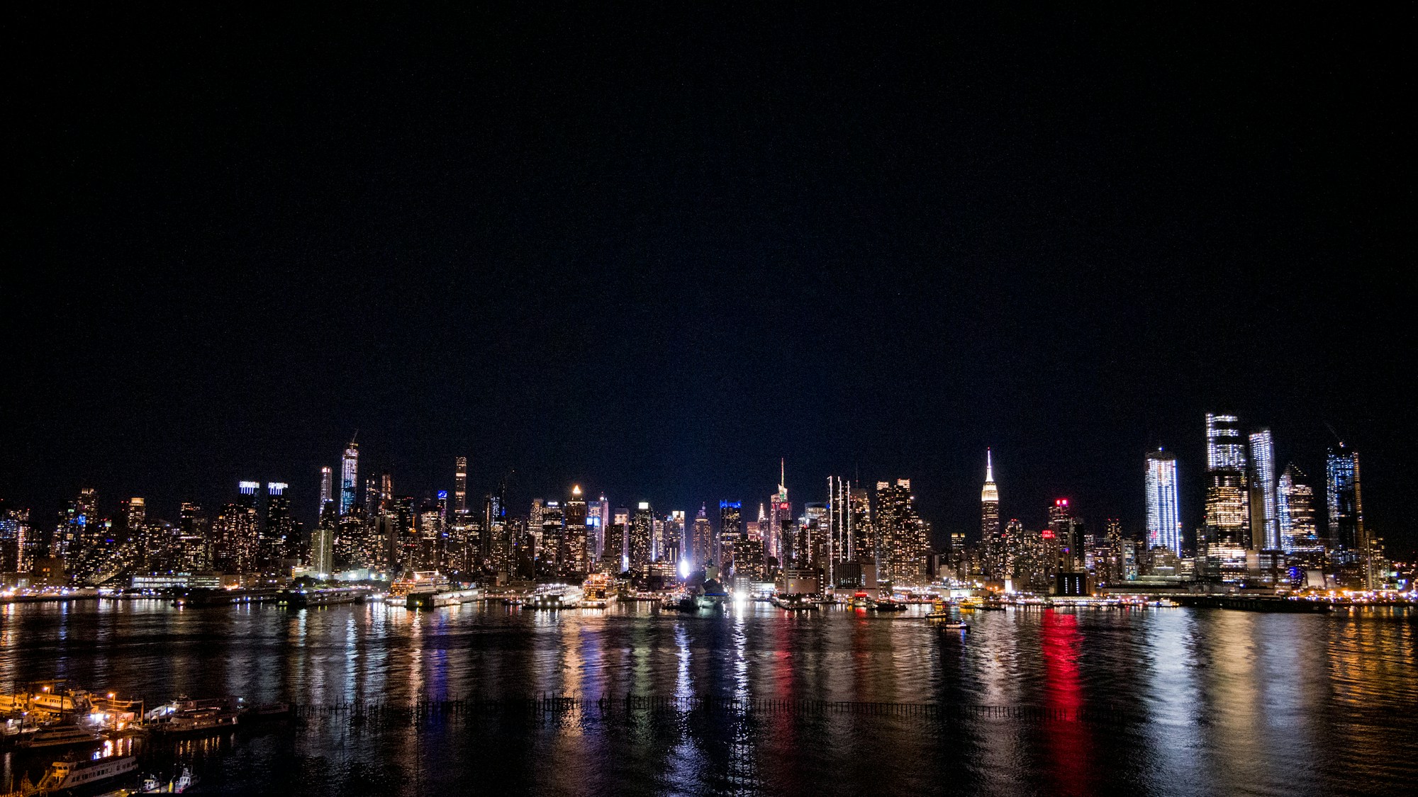 Night panorama of Manhattan in New York with its illuminated skyscrapers reflected in the Hudson River