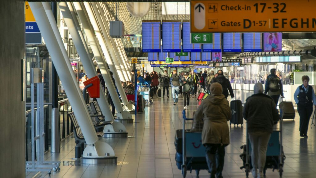 Hall d'enregistrement d'un aéroport international avec files d'attente et comptoirs — crise du Moyen-Orient 2026