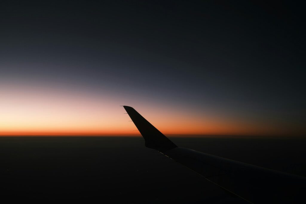 Aile d'avion contre un ciel sombre au coucher du soleil — crise du kérosène aviation 2026