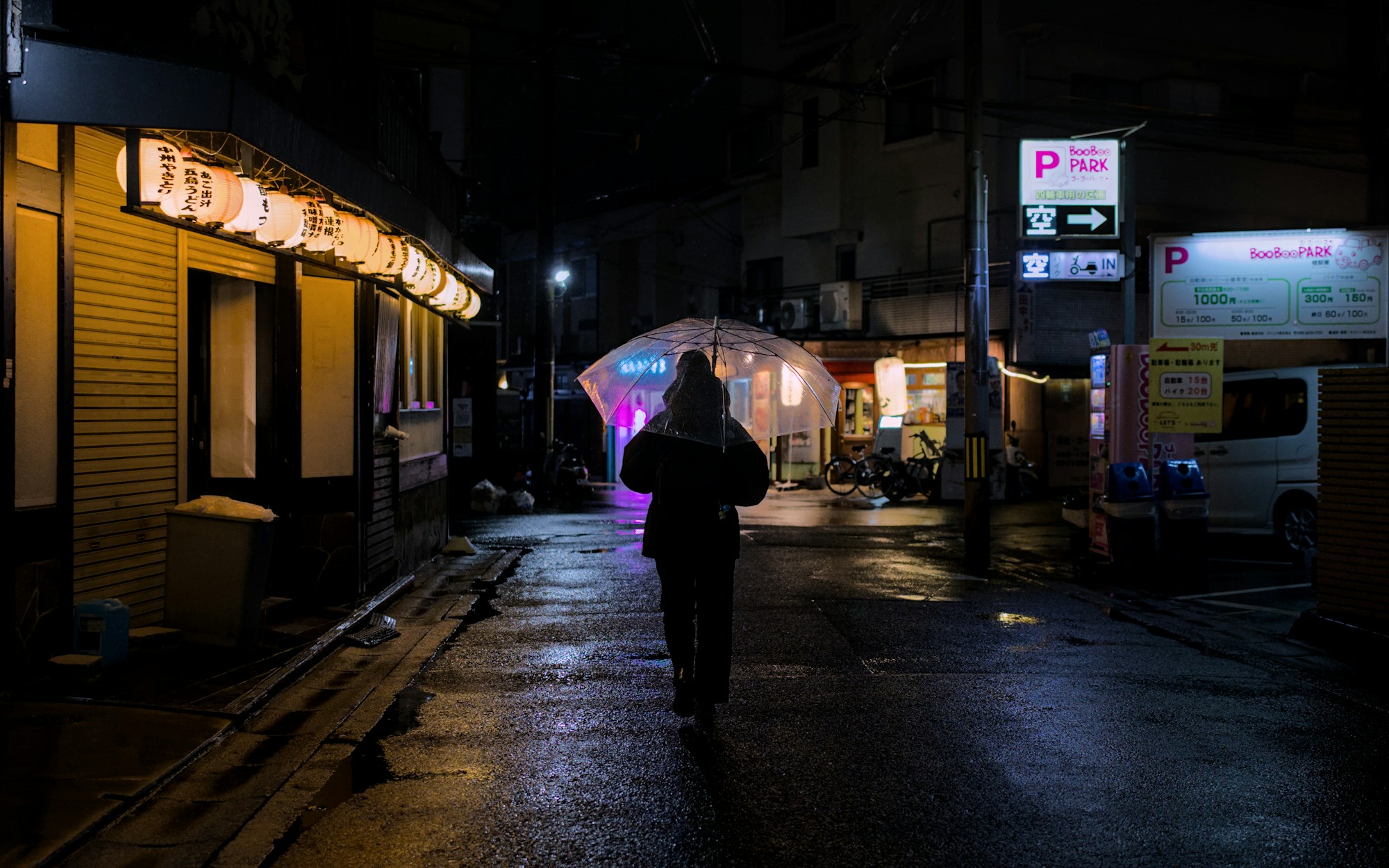 Person geht nachts durch eine neonbeleuchtete Gasse, Symbol für Stadtsicherheit im Ausland