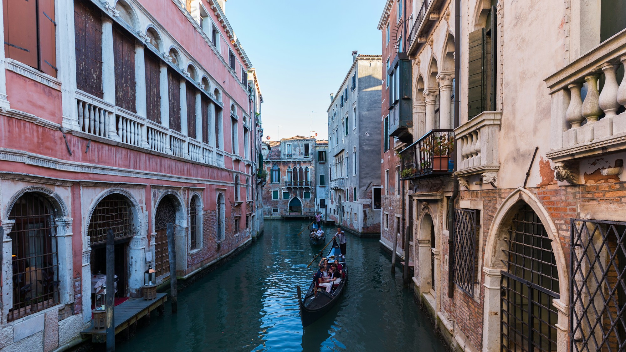 Gondolier sur un canal de Venise entre des bâtiments vénitiens historiques au coucher du soleil, ambiance sérénissime
