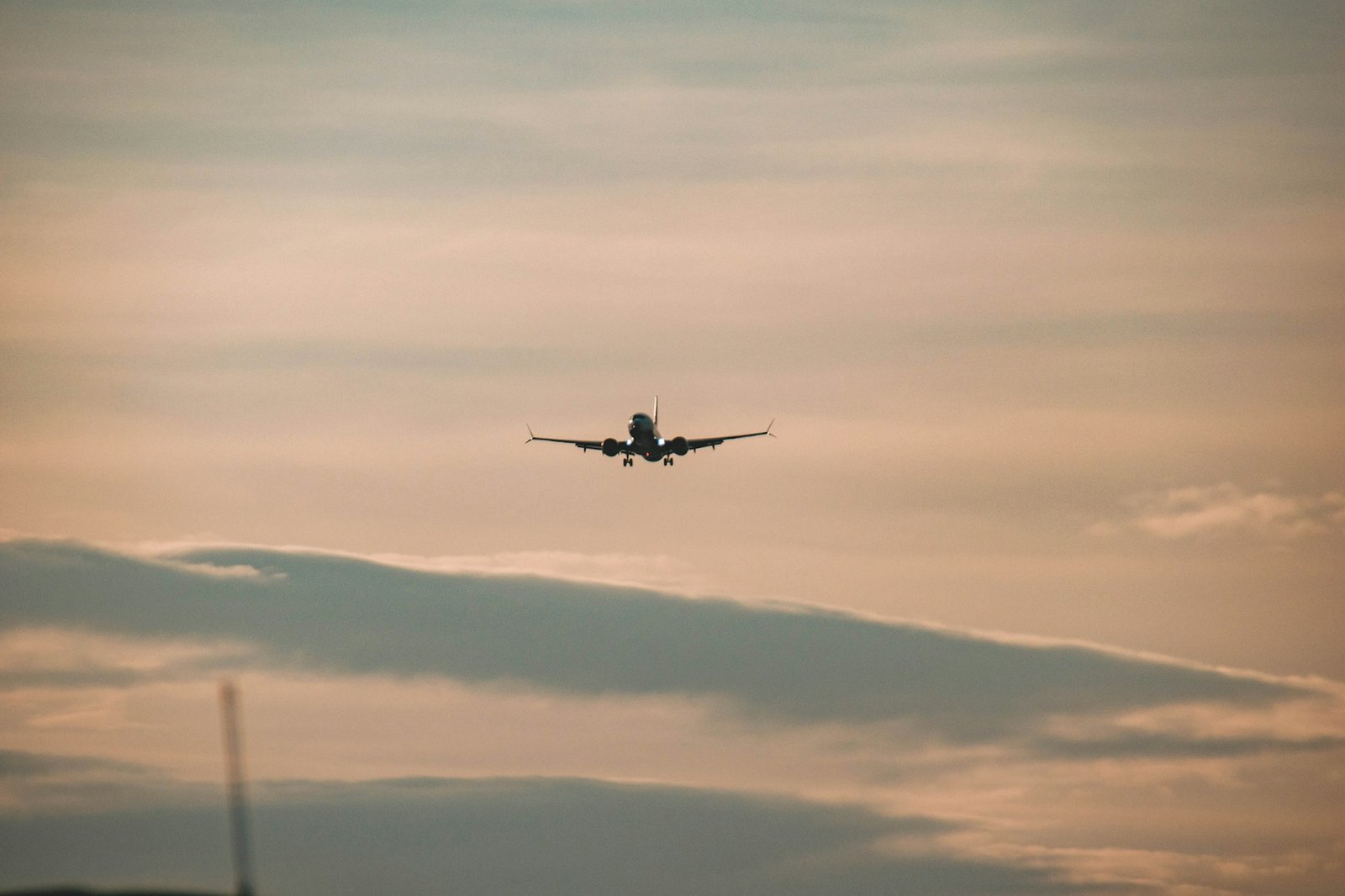 Avion de ligne en vol dans un ciel orangé au coucher du soleil — impact de la crise du kérosène sur les prix des billets d'avion