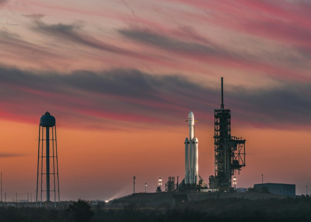 Fusée SpaceX sur rampe de lancement sous des nuages dorés — zones de sécurité et débris de missiles