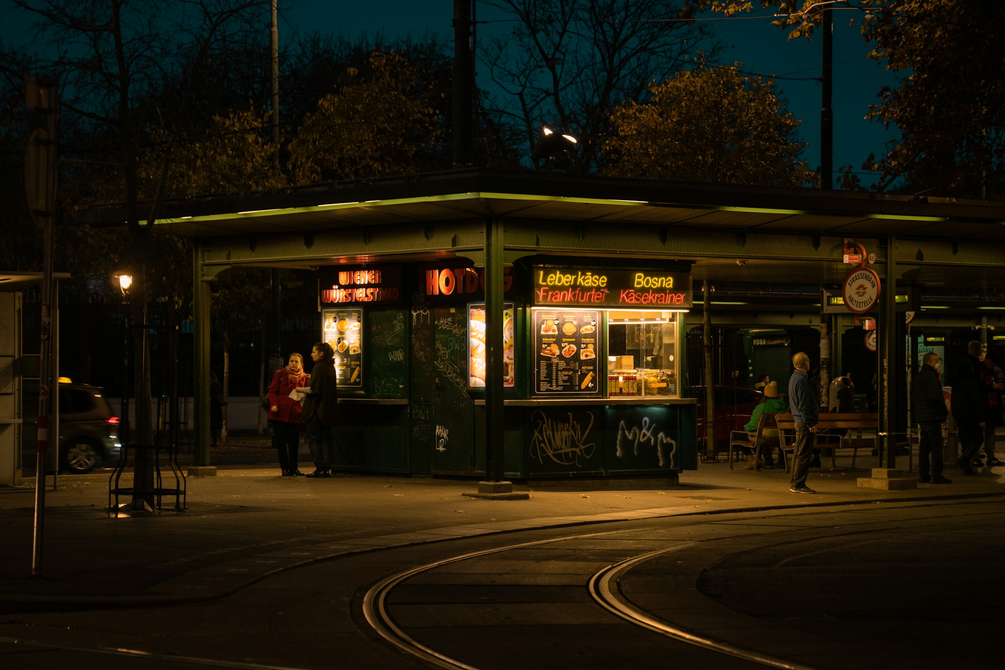 Beleuchtete Wiener Verkehrsstation bei Nacht mit Fahrgästen, die die hervorragenden ÖPNV-Verbindungen zur Stadthalle verdeutlicht