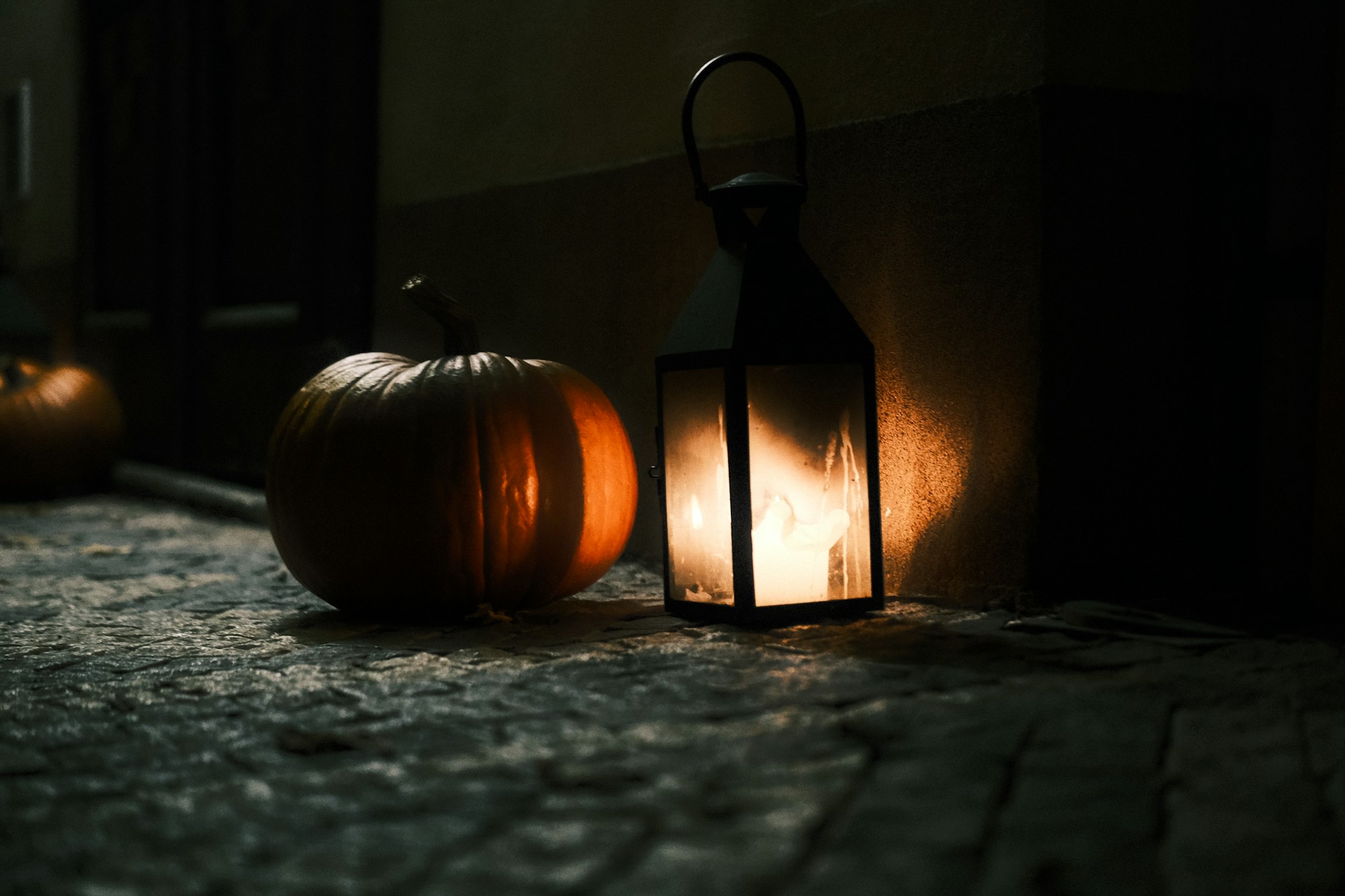 Lantern and pumpkin on a cobblestone path at night, gothic Halloween atmosphere