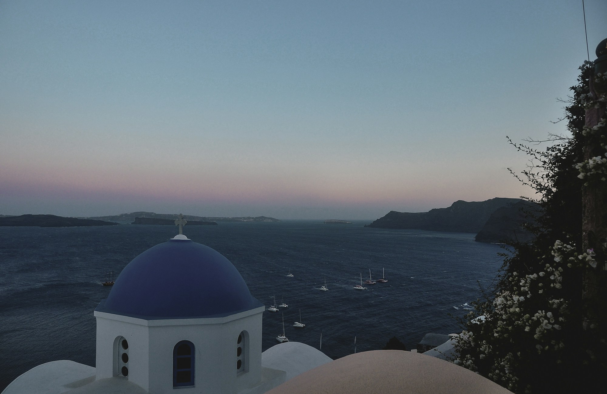 Tramonto spettacolare sulla caldera di Santorini con le iconiche case bianche e le cupole blu, Grecia