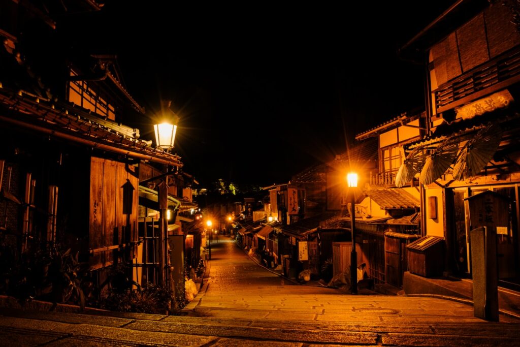 Rue historique japonaise illuminée par des lanternes traditionnelles de nuit à Kyoto