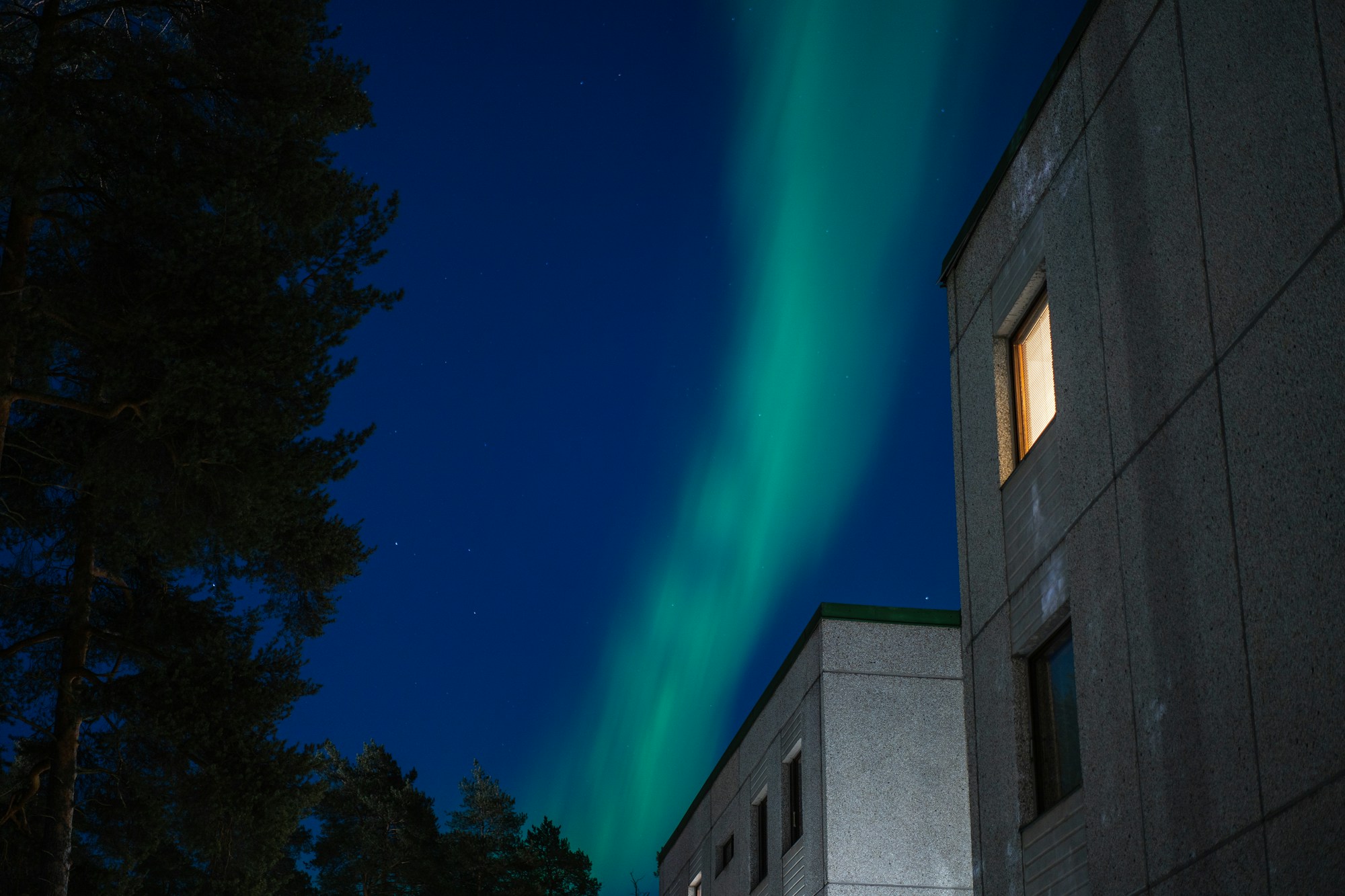 Aurores boréales vertes illuminant le ciel nocturne au-dessus de bâtiments finlandais