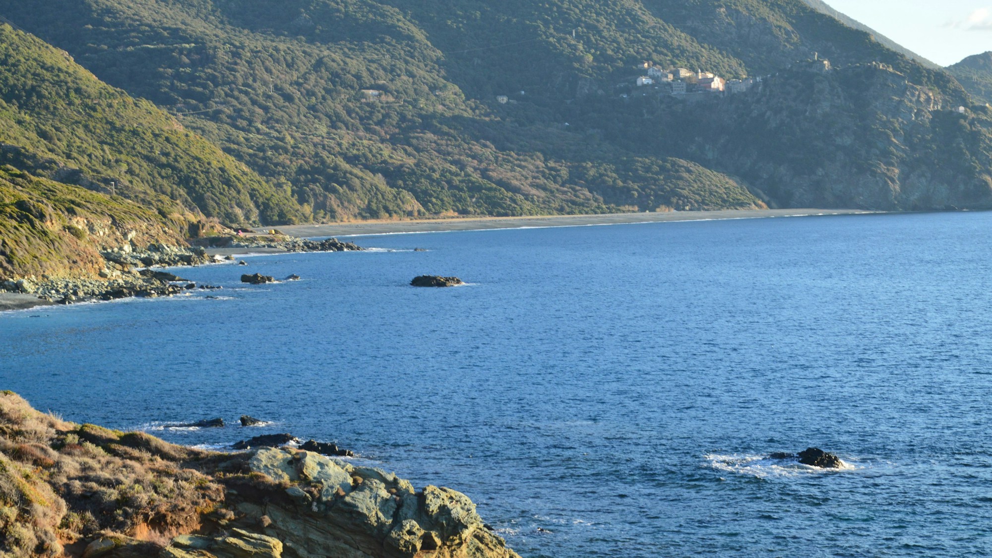 Côte rocheuse de la Corse avec eaux turquoise de la Méditerranée et collines verdoyantes