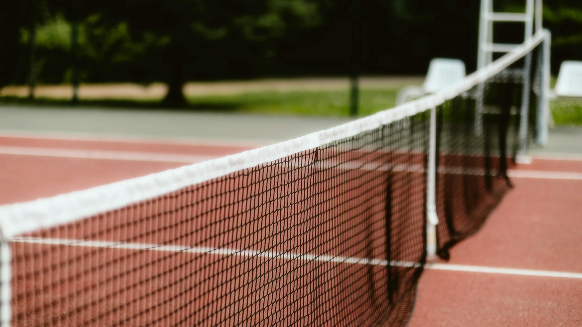 Spectators in wooden stands facing an outer court at Roland-Garros, just a few metres from a player in action on the clay