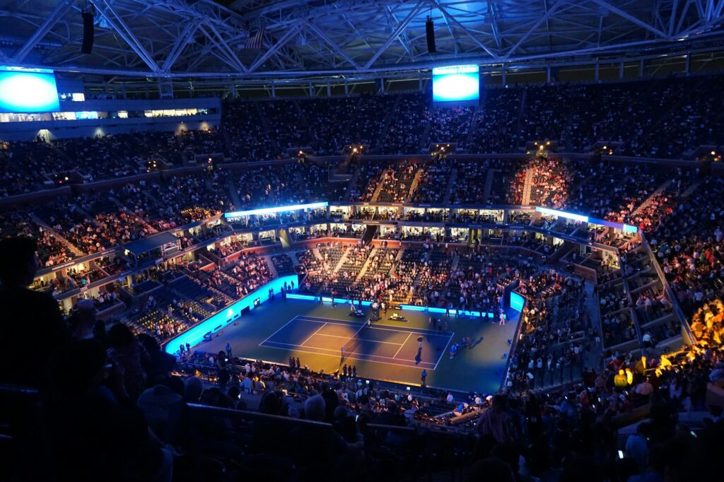 Arthur Ashe Stadium éclairé la nuit — ambiance similaire aux night sessions de Roland-Garros 2026