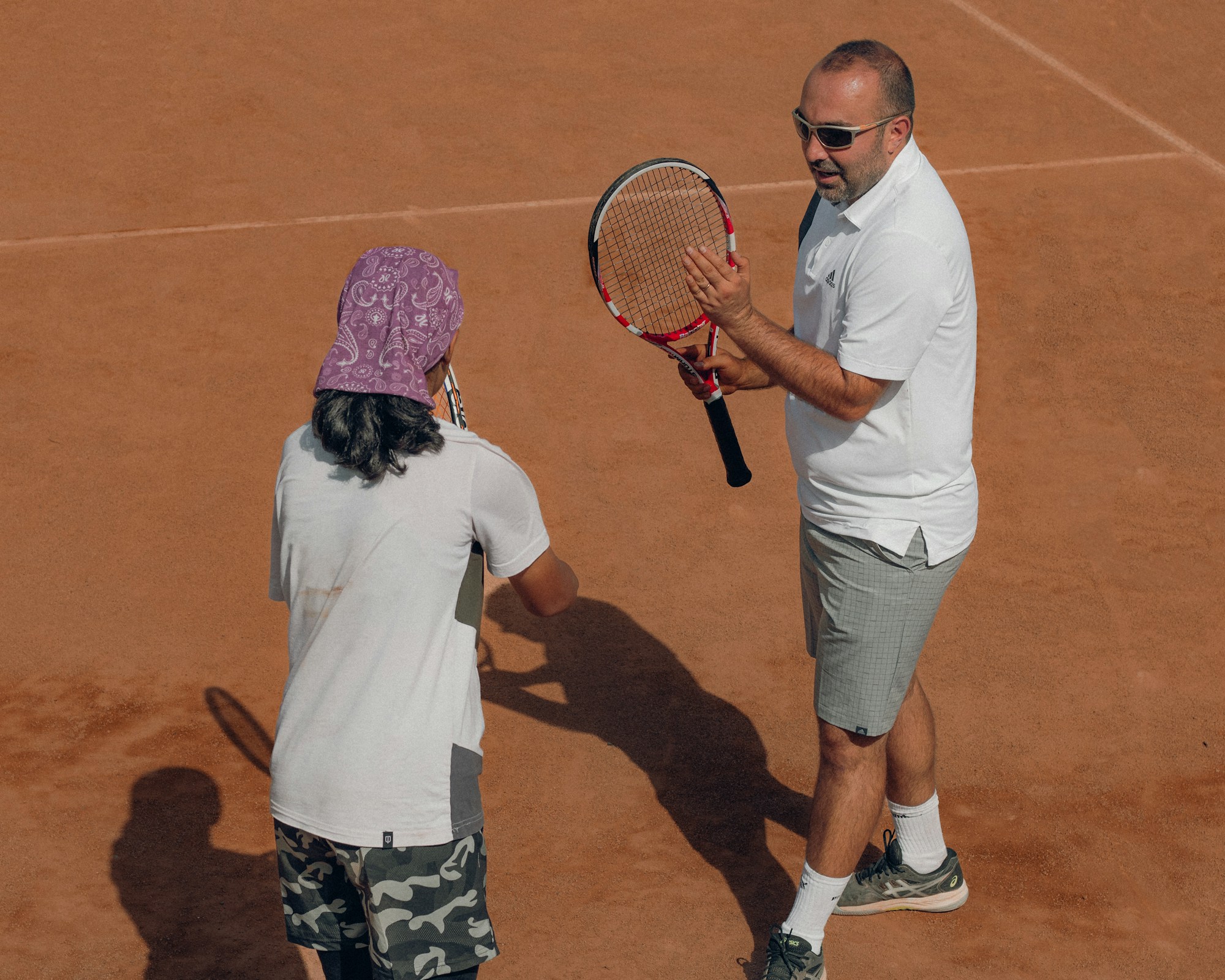 Family with children watching a tennis match at Roland-Garros, smiling in the stands on a sunny day