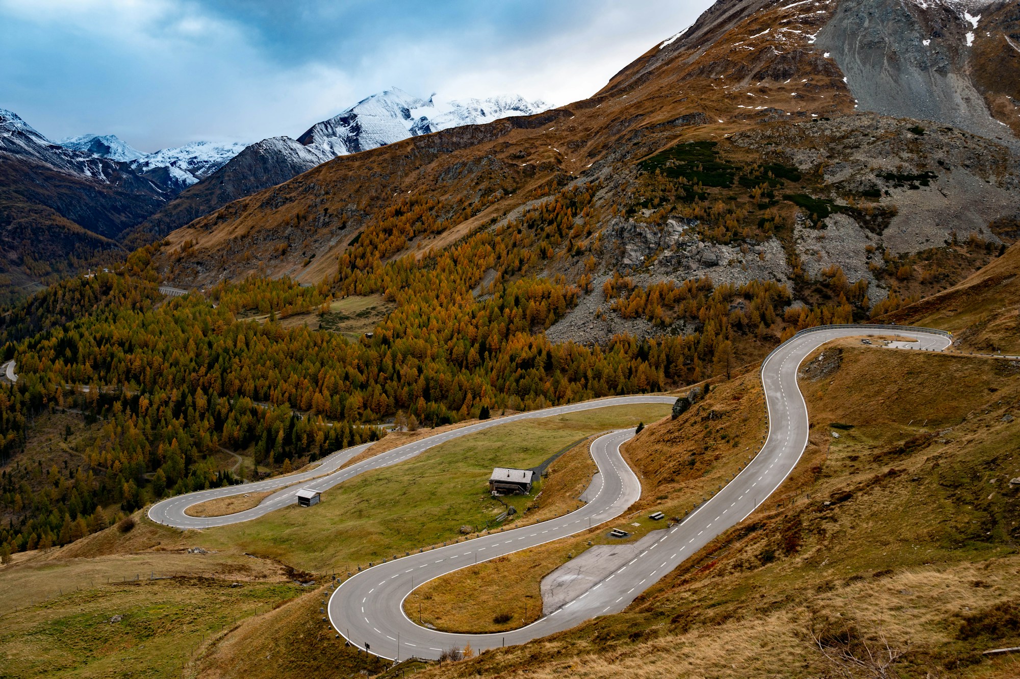 Winding mountain road through the Alps with snow-capped peaks in the background