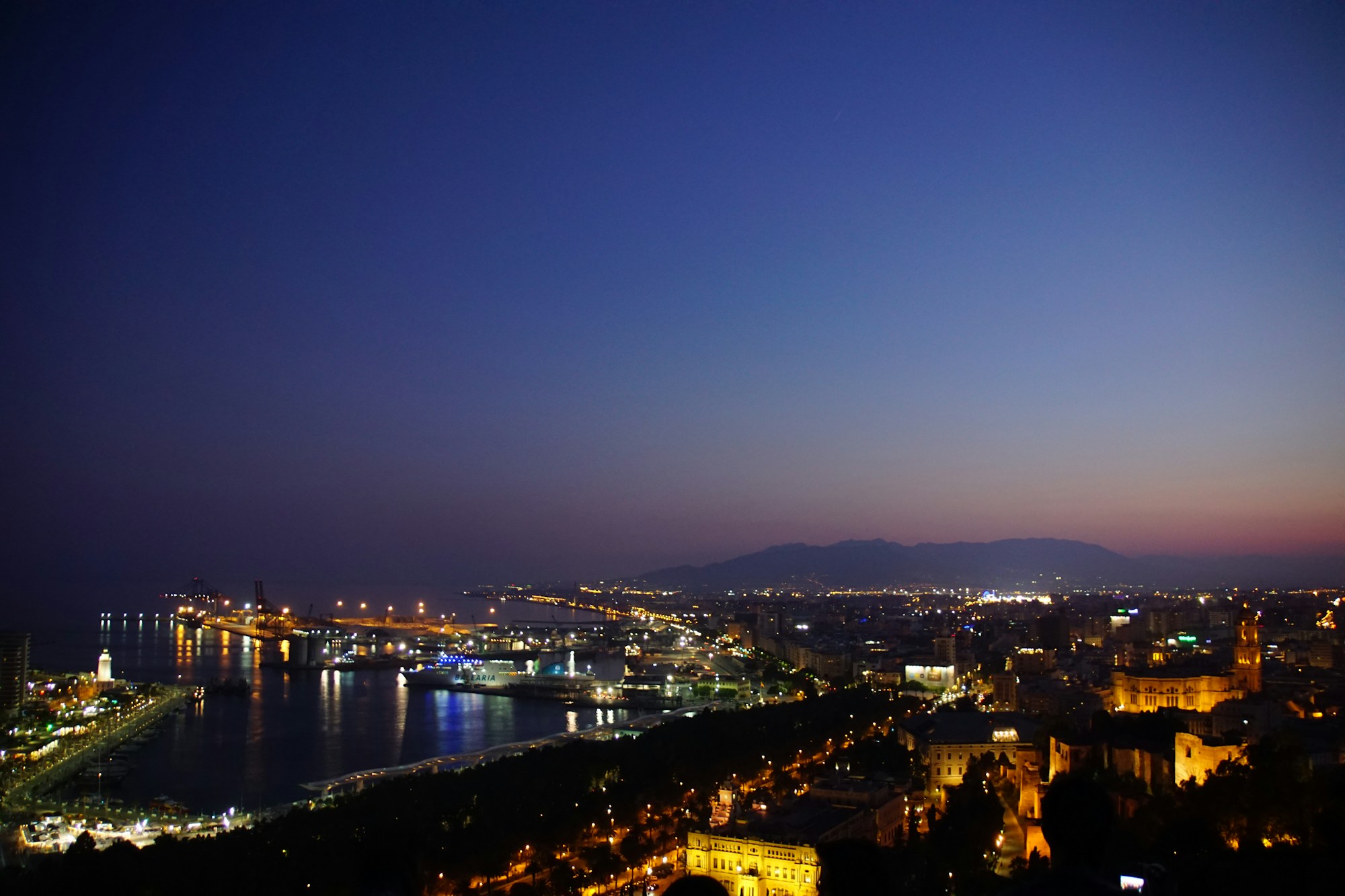 Malaga port at dusk with the city and mountains in the background