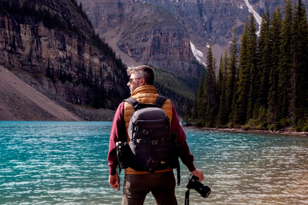 Voyageur avec sac à dos devant un lac de montagne, voyage pas cher 2026