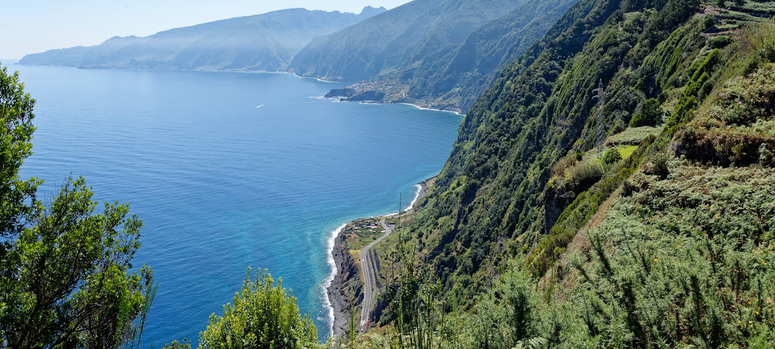 Sentier levada de Madère bordé de végétation luxuriante, randonneurs sur le chemin en corniche