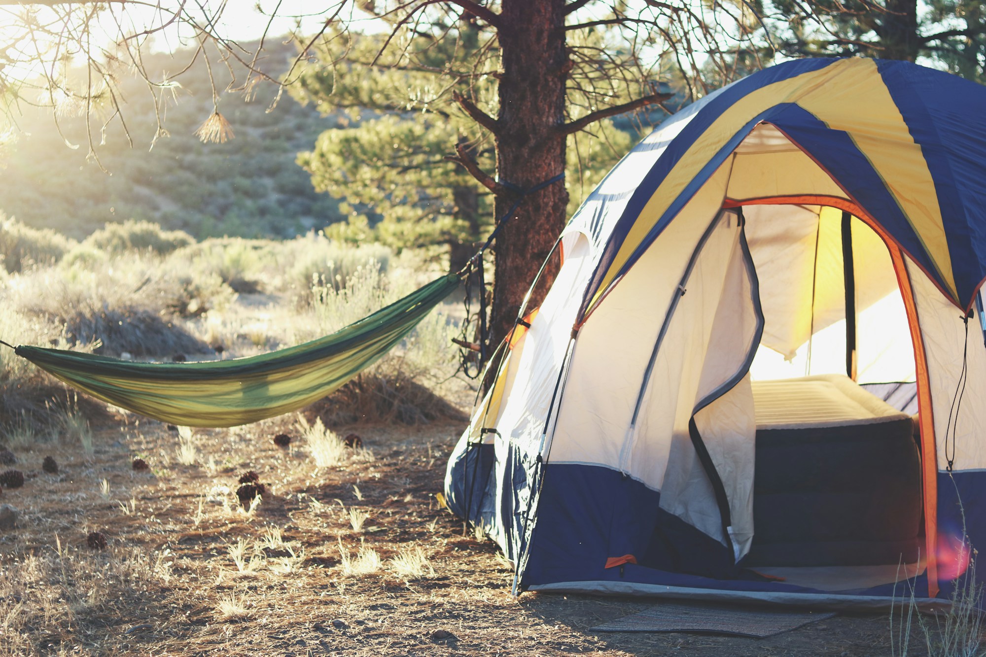Campement de festivaliers avec rangées de tentes colorées au coucher de soleil lors d'un grand festival d'été