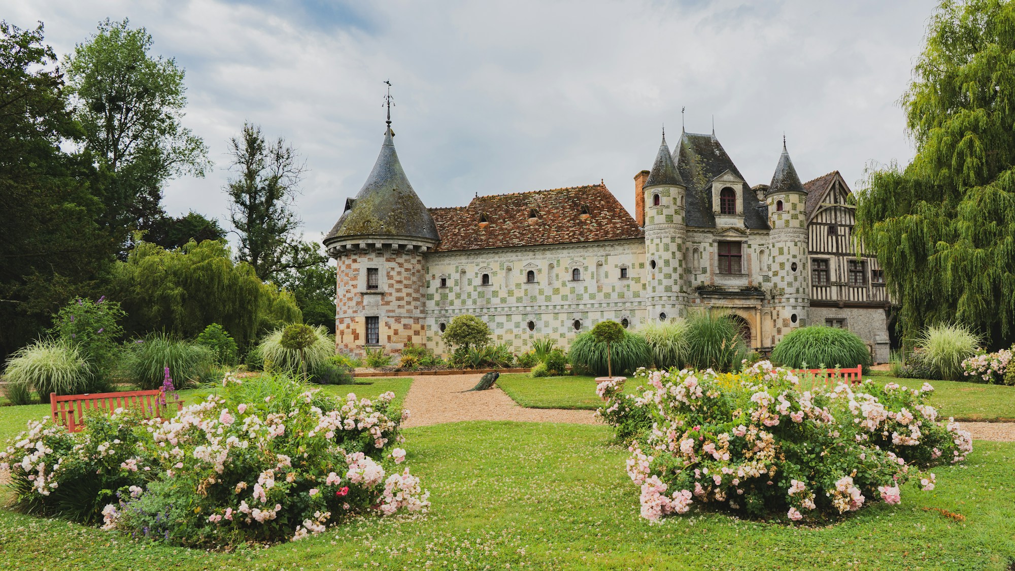 Château entouré de jardins de roses en pleine floraison en juin