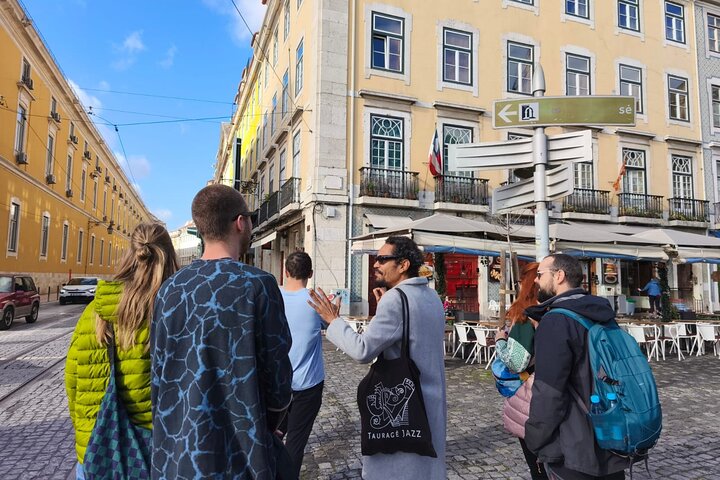 Guide avec parapluie orange sur la Praça do Comércio au départ du tour Alfama et Mouraria plus anciens quartiers de Lisbonne