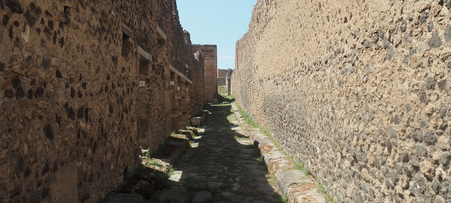 Basalt-paved street in Pompeii with chariot ruts carved into the stone and the ruins of Roman houses