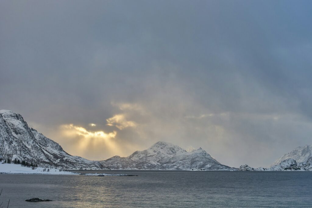 Soleil de minuit sur l'océan Arctique en Norvège, lumière dorée rasant l'horizon à minuit