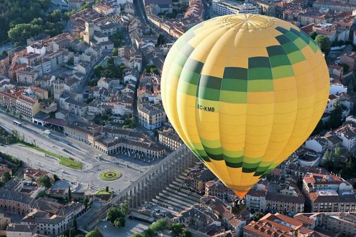 Montgolfière au lever du soleil survolant l'aqueduc et l'Alcázar de Ségovie avec la Sierra de Guadarrama en arrière-plan