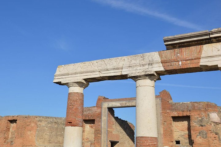 Small group of visitors exploring the ruins of Pompeii in late afternoon golden light
