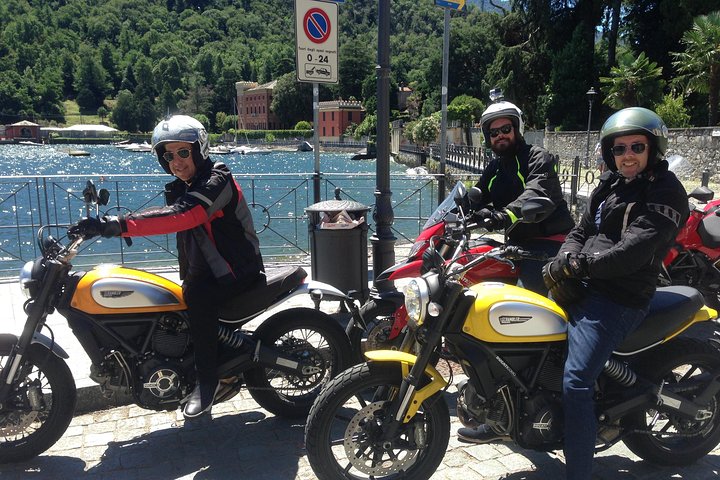 Moto Ducati sur une route alpine panoramique surplombant le lac de Côme et les Alpes lombardes