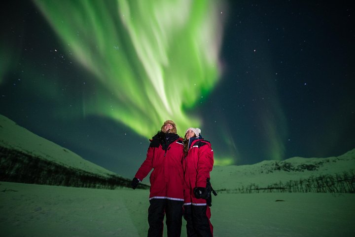 Petit groupe habillé en combinaison thermique sous les aurores boréales, Tromsø