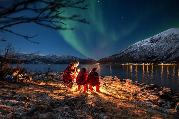 Groupe en extérieur sous les aurores boréales à Tromsø, feu de camp arctique