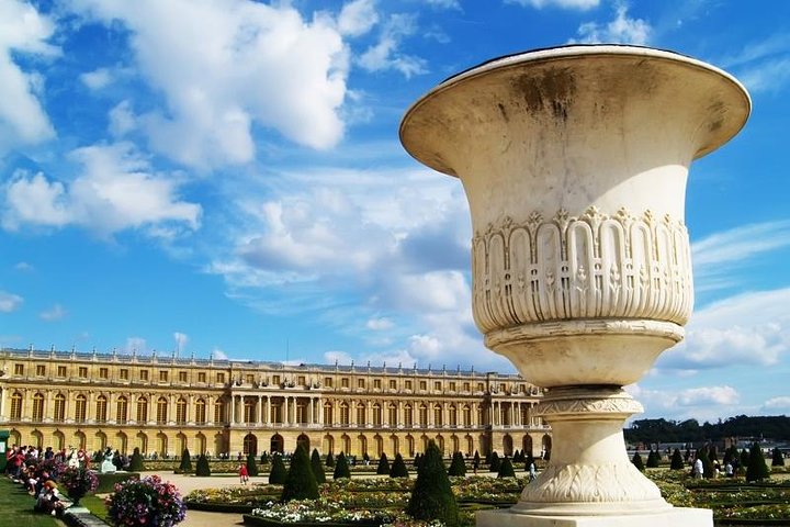 Groupe de visiteurs devant l'entrée principale du château de Versailles avec guide