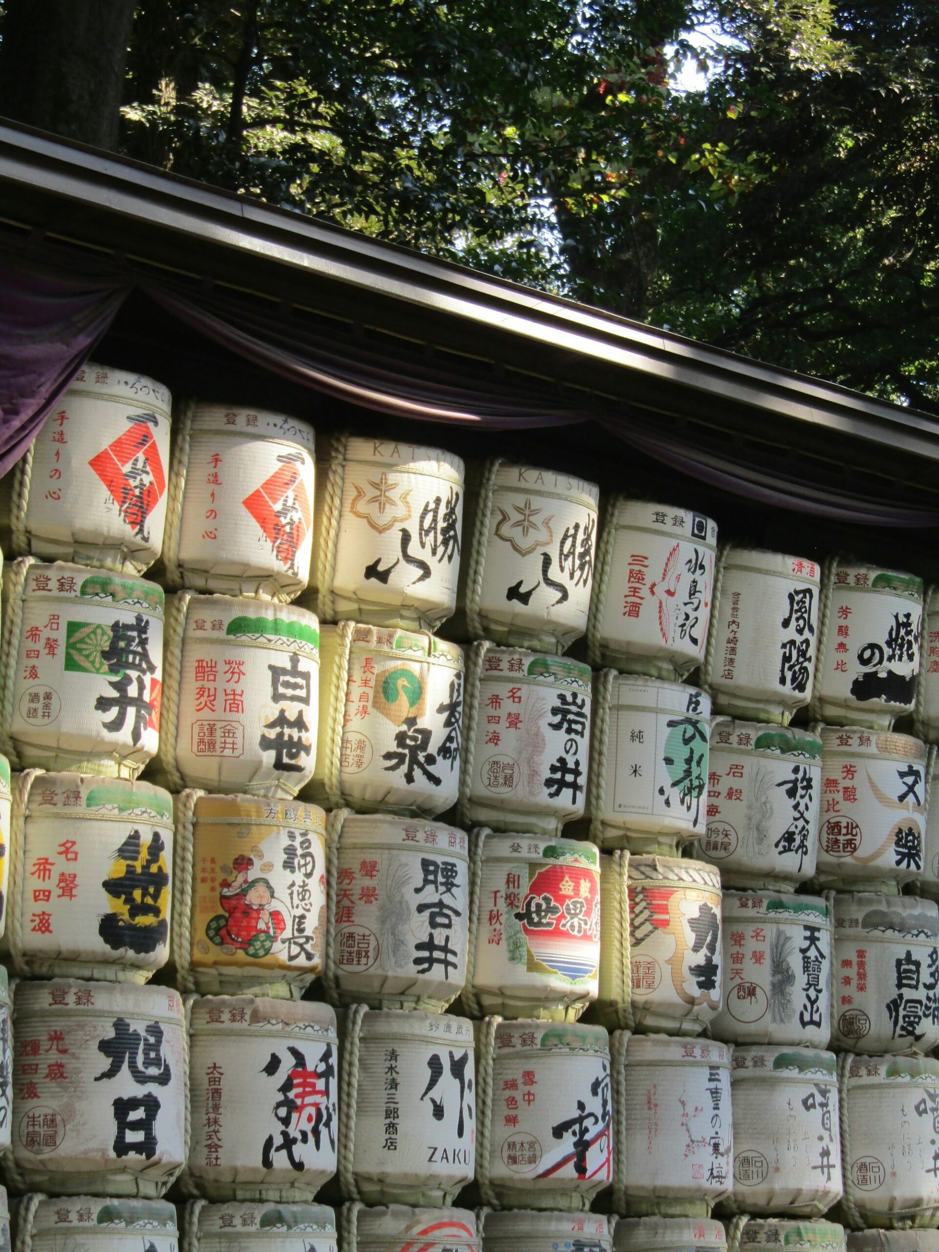 Botti tradizionali di sake impilate, decorate con calligrafia giapponese