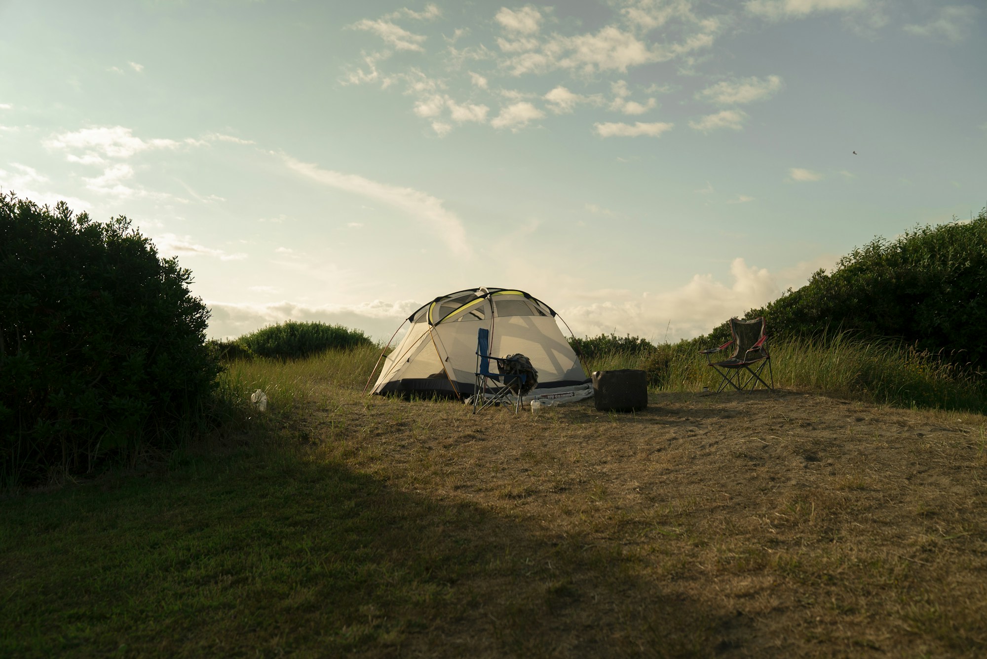 Tienda blanca plantada en un campo de hierba, imagen del camping general en un festival