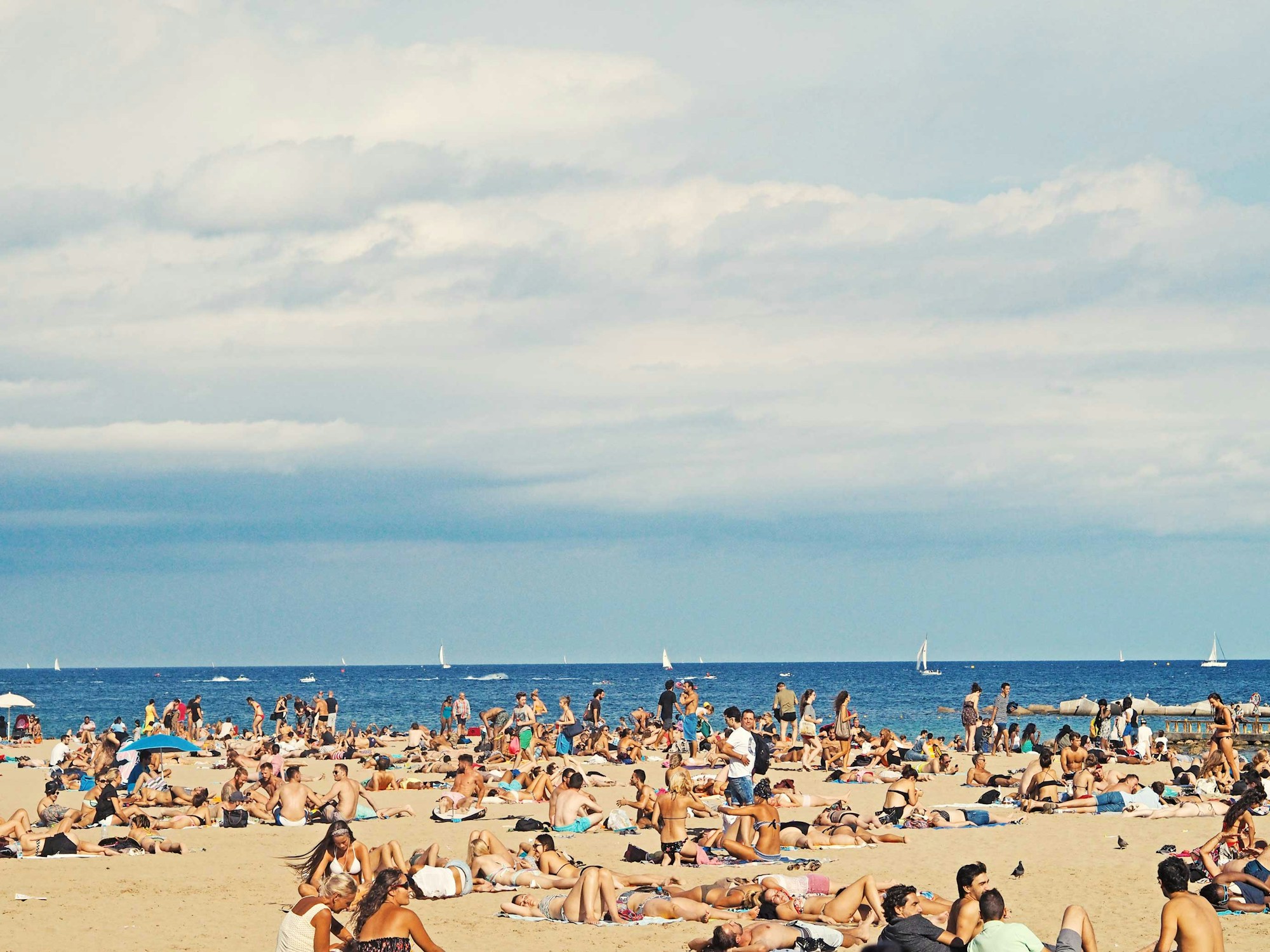 Plage méditerranéenne en été avec parasols, affluence touristique en août