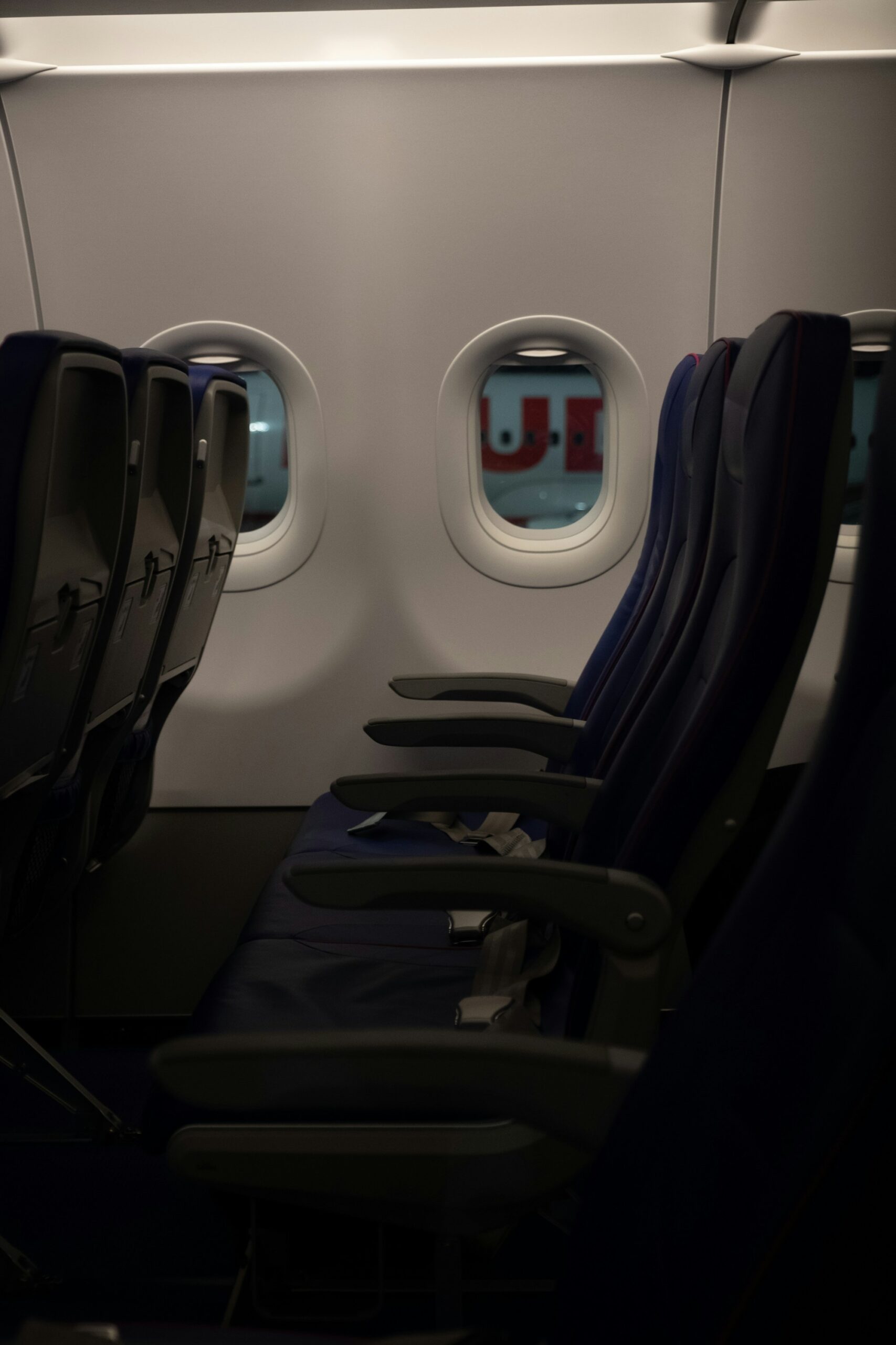 Leere Sitzreihe in einer Flugzeugkabine, die den verfügbaren Platz unter dem Sitz für einen persönlichen Gegenstand veranschaulicht