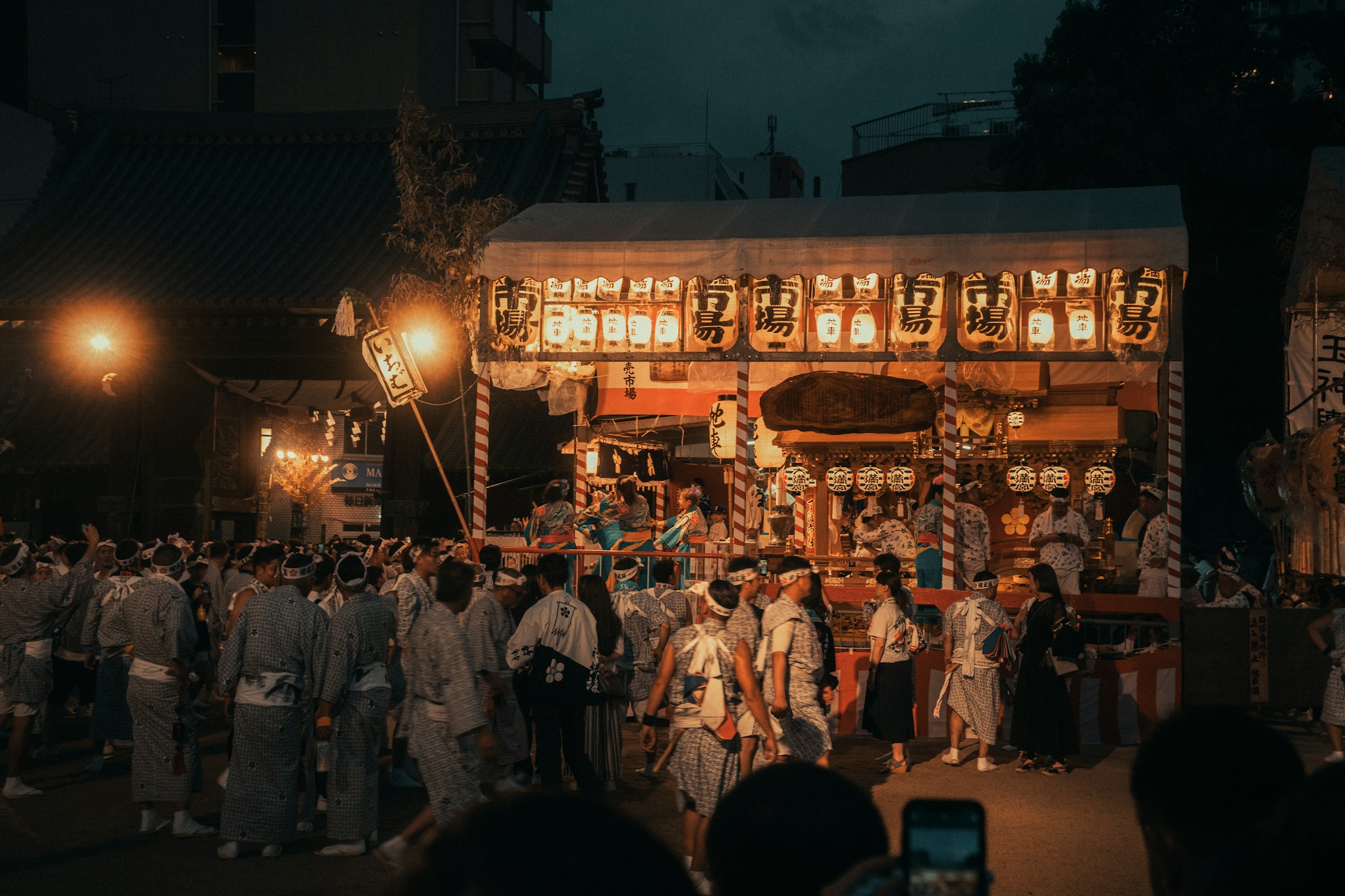 Foule rassemblée en soirée dans une rue animée au Japon