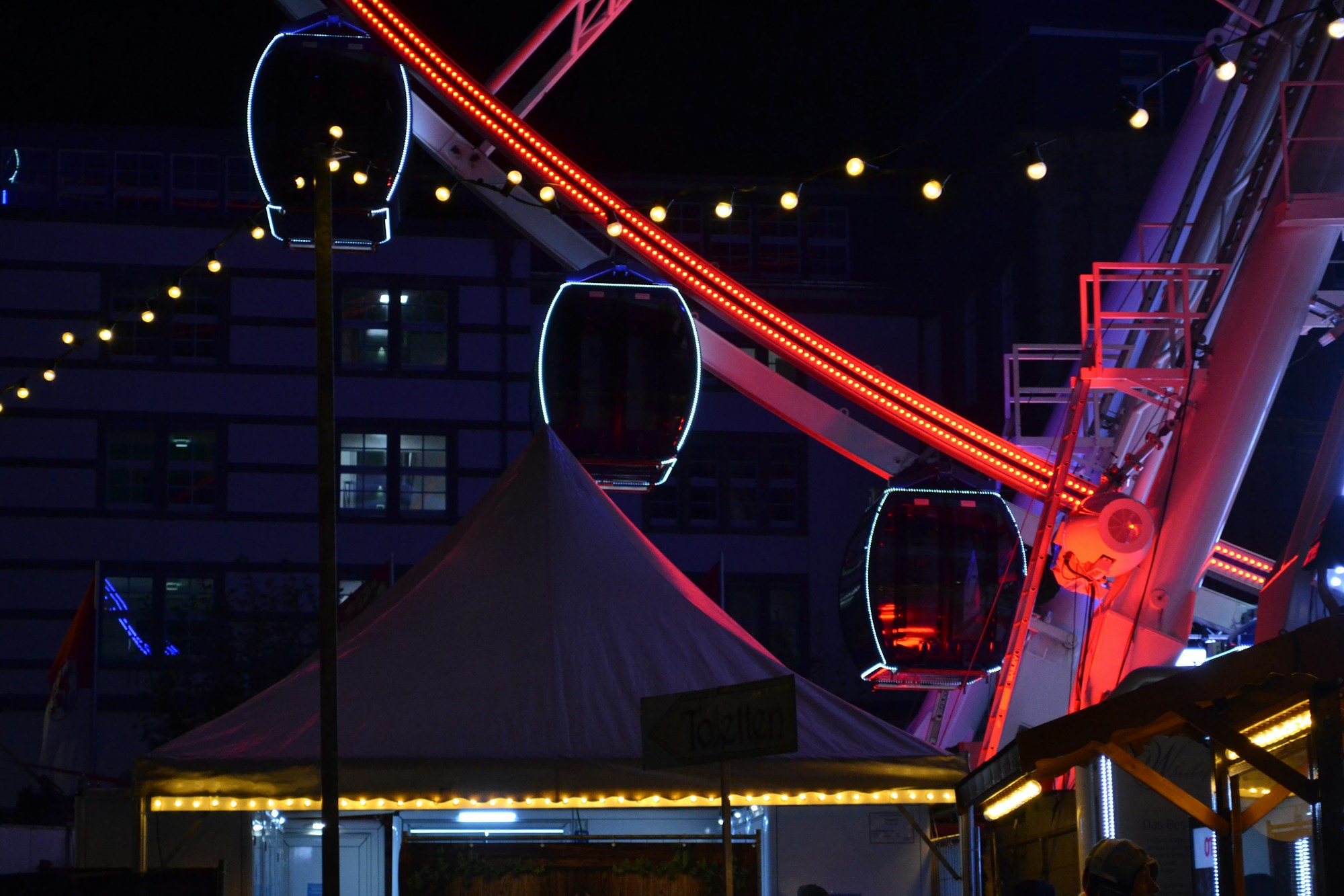 Grande roue illuminée la nuit, ambiance de fête foraine à Sideshow Alley
