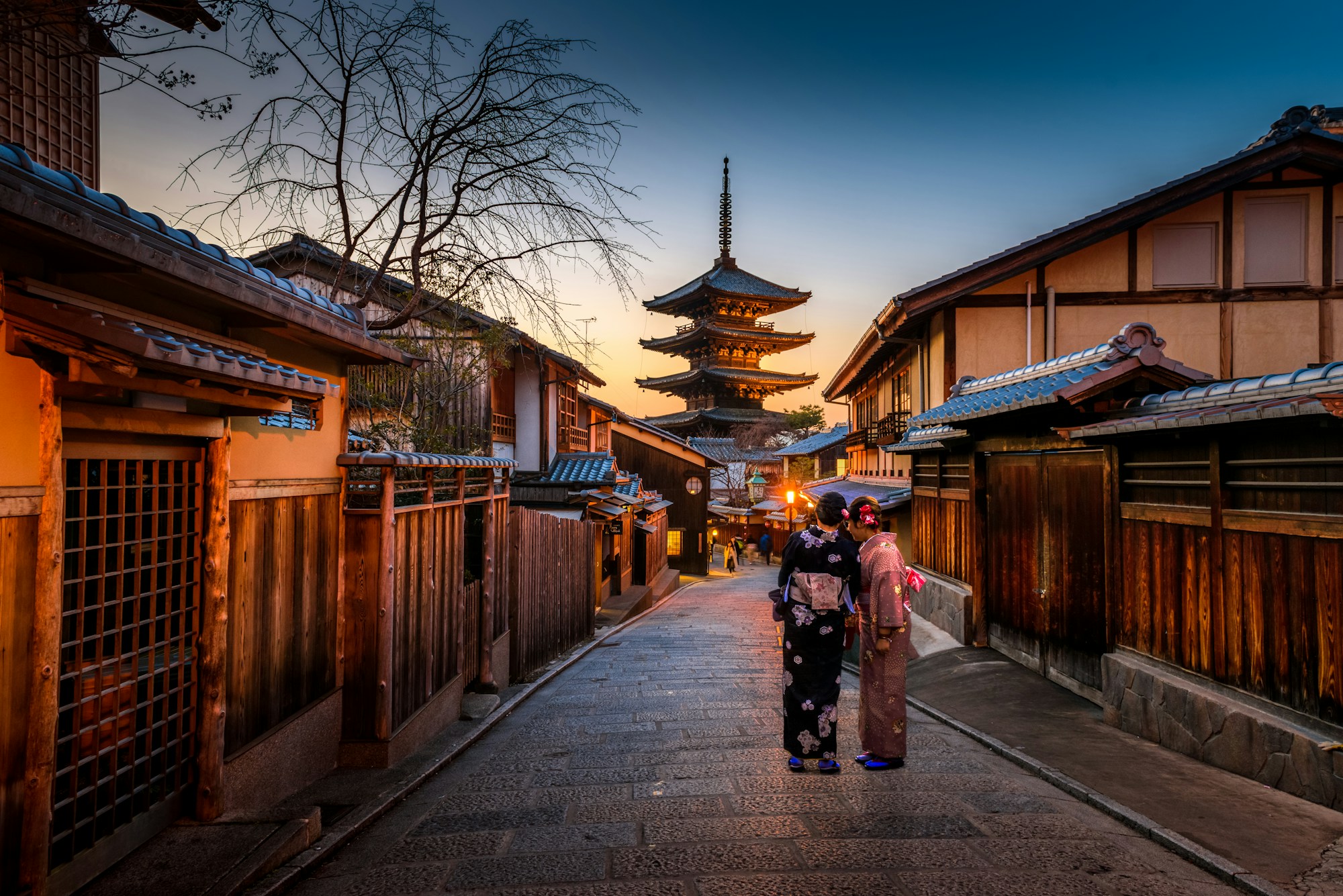 Women in kimono walking a Higashiyama lane at dusk, Yasaka Pagoda in the background
