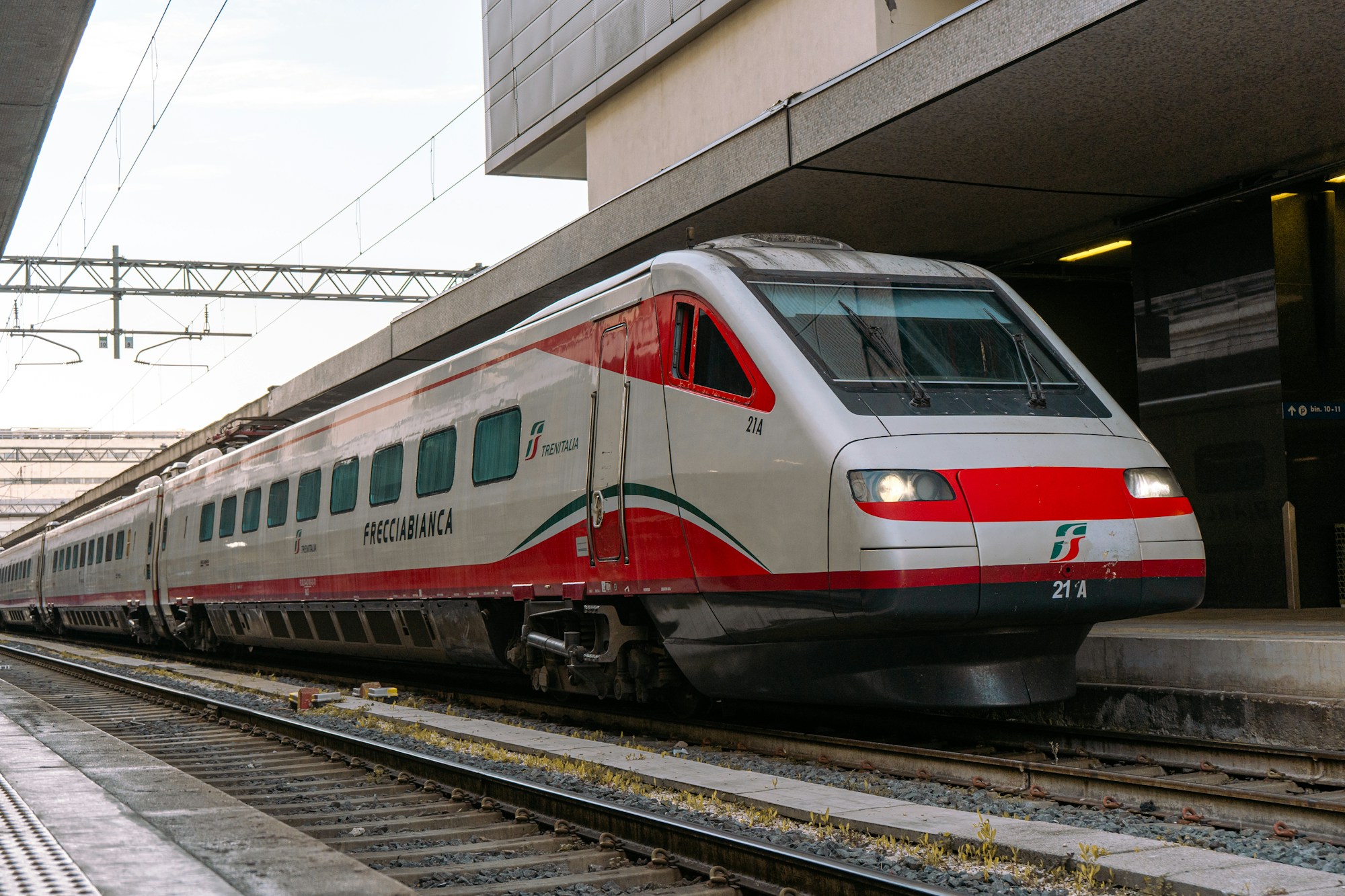 Tren regional rojo y blanco en un andén de una estación italiana