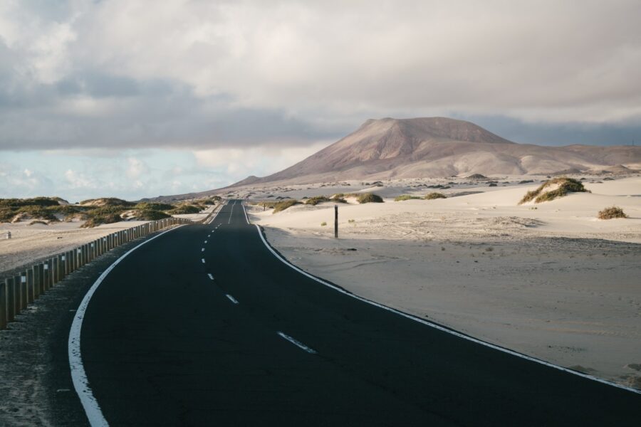 Route traversant les dunes de sable de Corralejo à Fuerteventura, collines volcaniques en arrière-plan