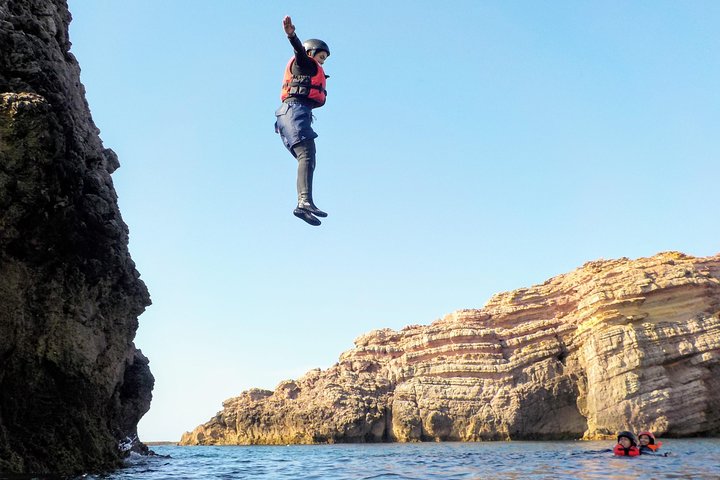 Tuffo dalle rocce durante una sessione di coasteering sulla costa tra Lagos e Sagres