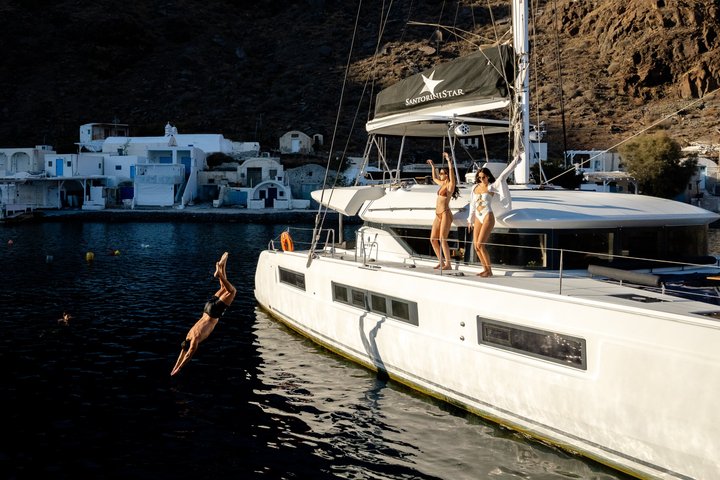 Premium catamaran approaching Oia at sunset in Santorini
